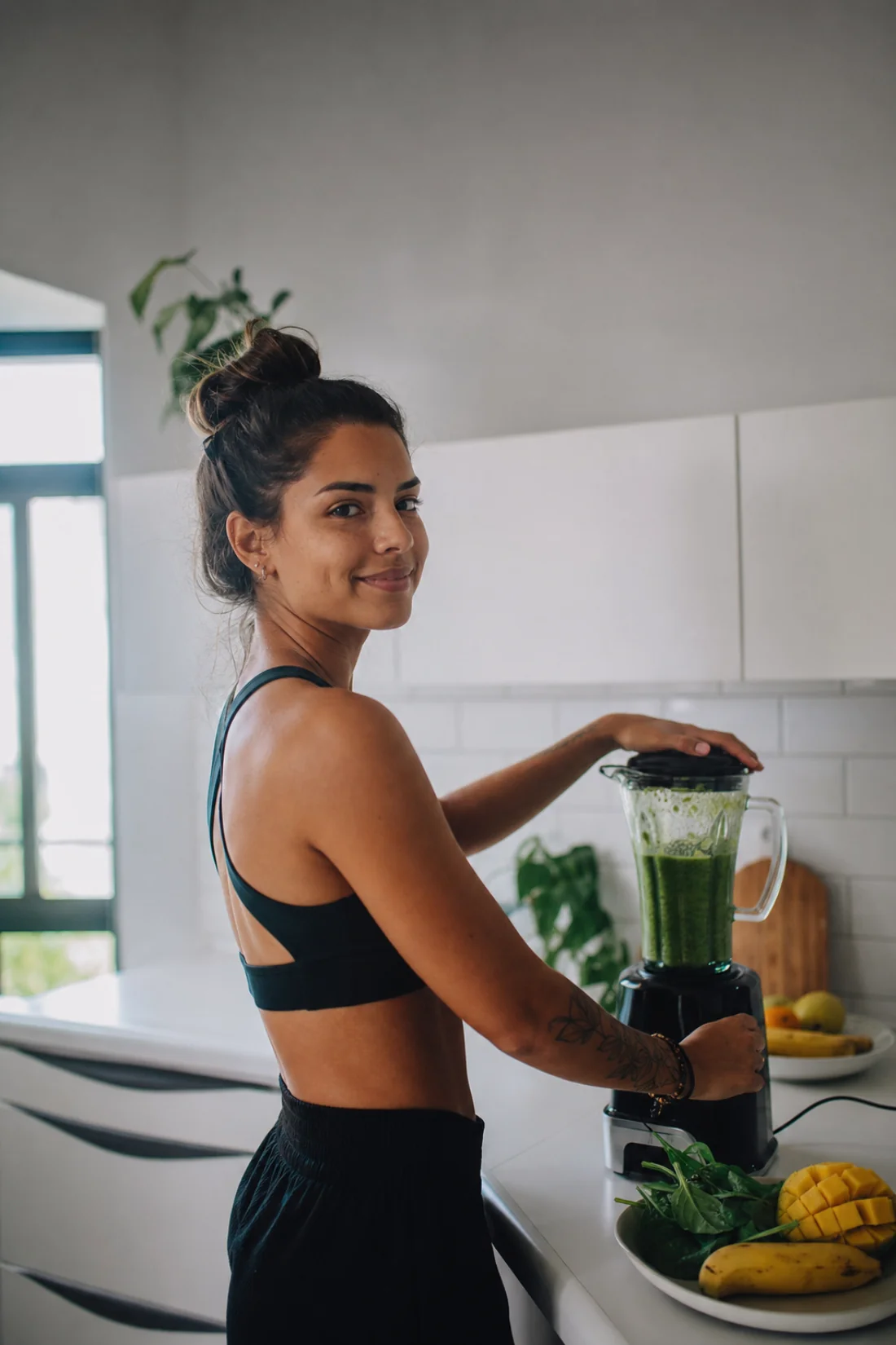 Mulher batendo um smoothie verde na cozinha de casa